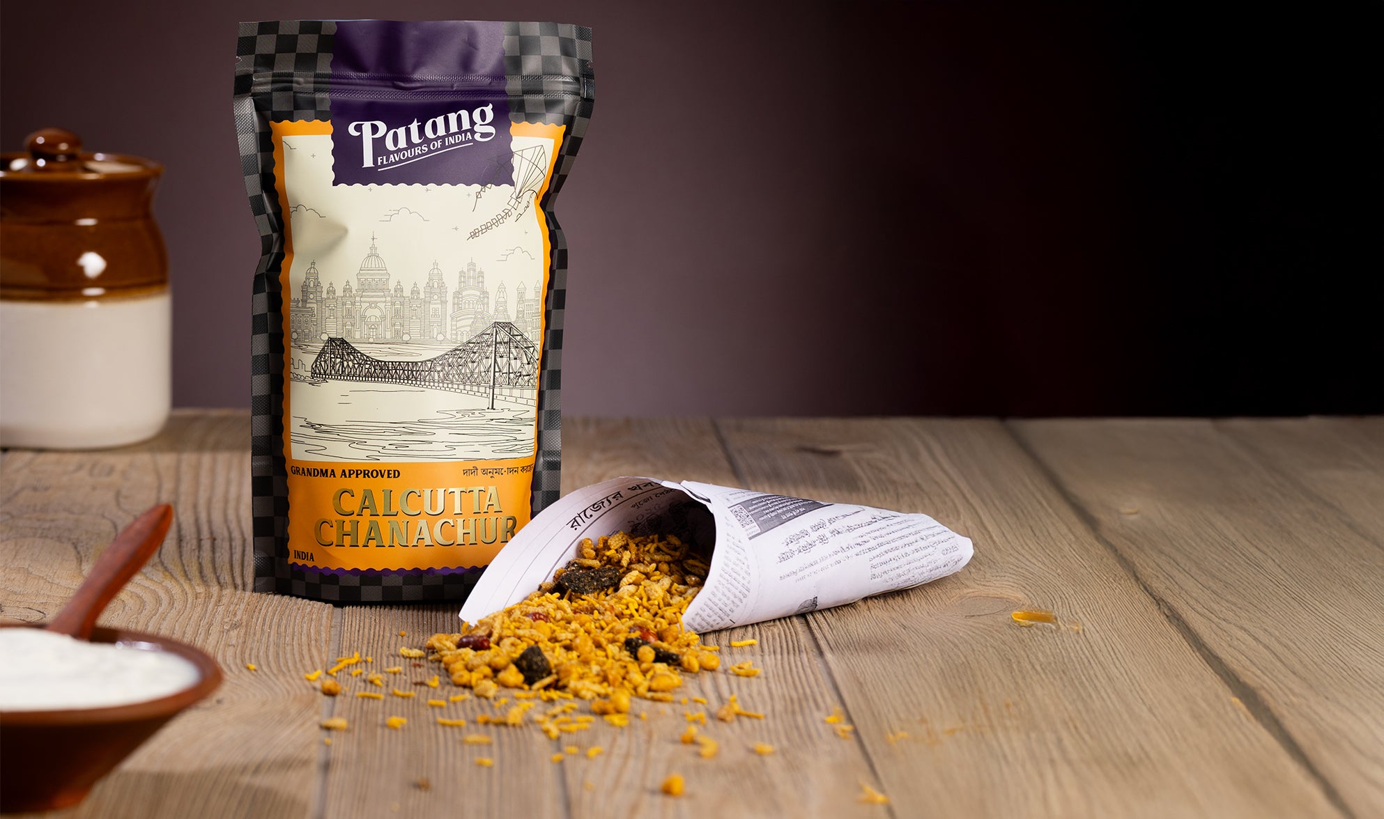 Open bag of Patang Calcutta Chanachur on a wooden surface with a dark background
