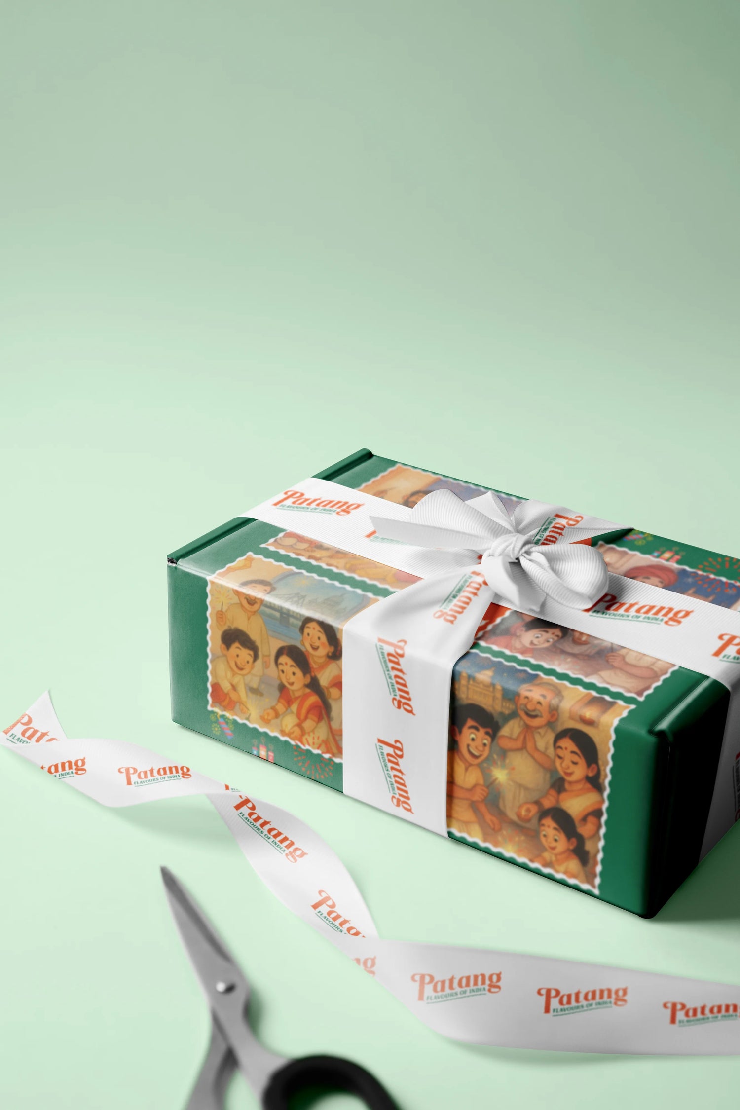 Gift box wrapped with Patang brand ribbon and scissors on a light green background