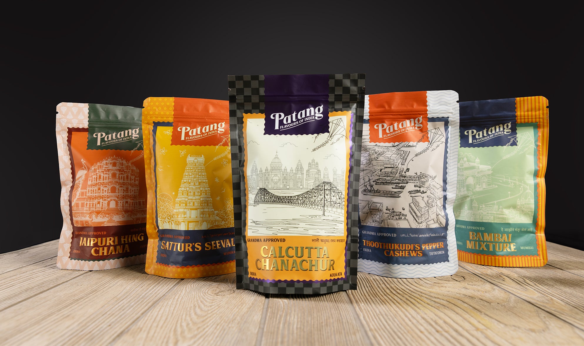 Five Patang brand packages on a wooden surface with a dark background